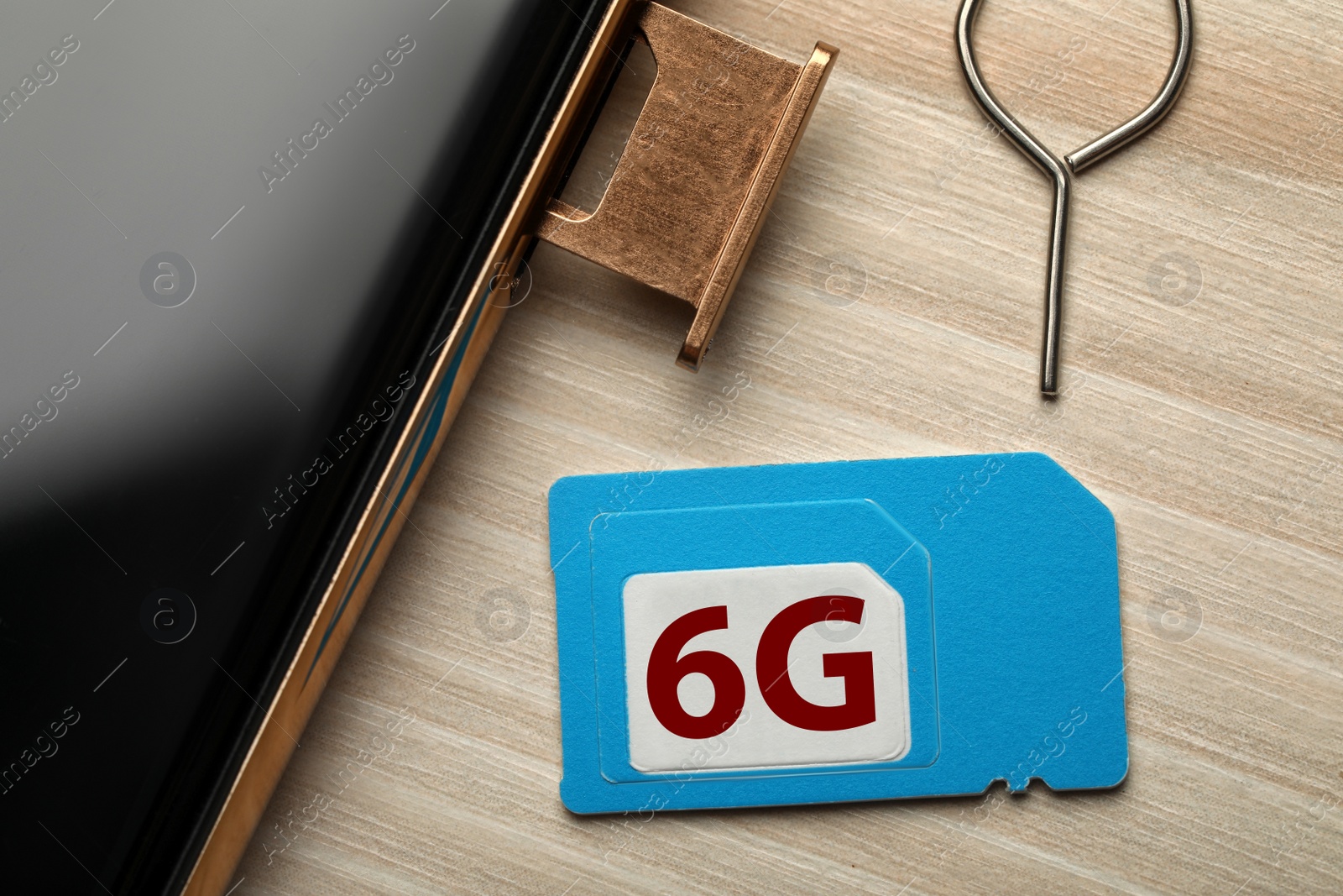 Photo of 6G technology, Internet concept. SIM card with smartphone on wooden table, closeup