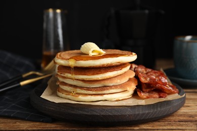 Photo of Delicious pancakes with maple syrup, butter and fried bacon on wooden table