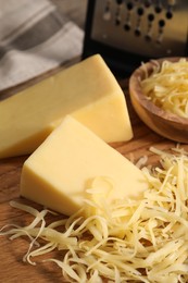 Photo of Grated and whole pieces of cheese on wooden table, closeup