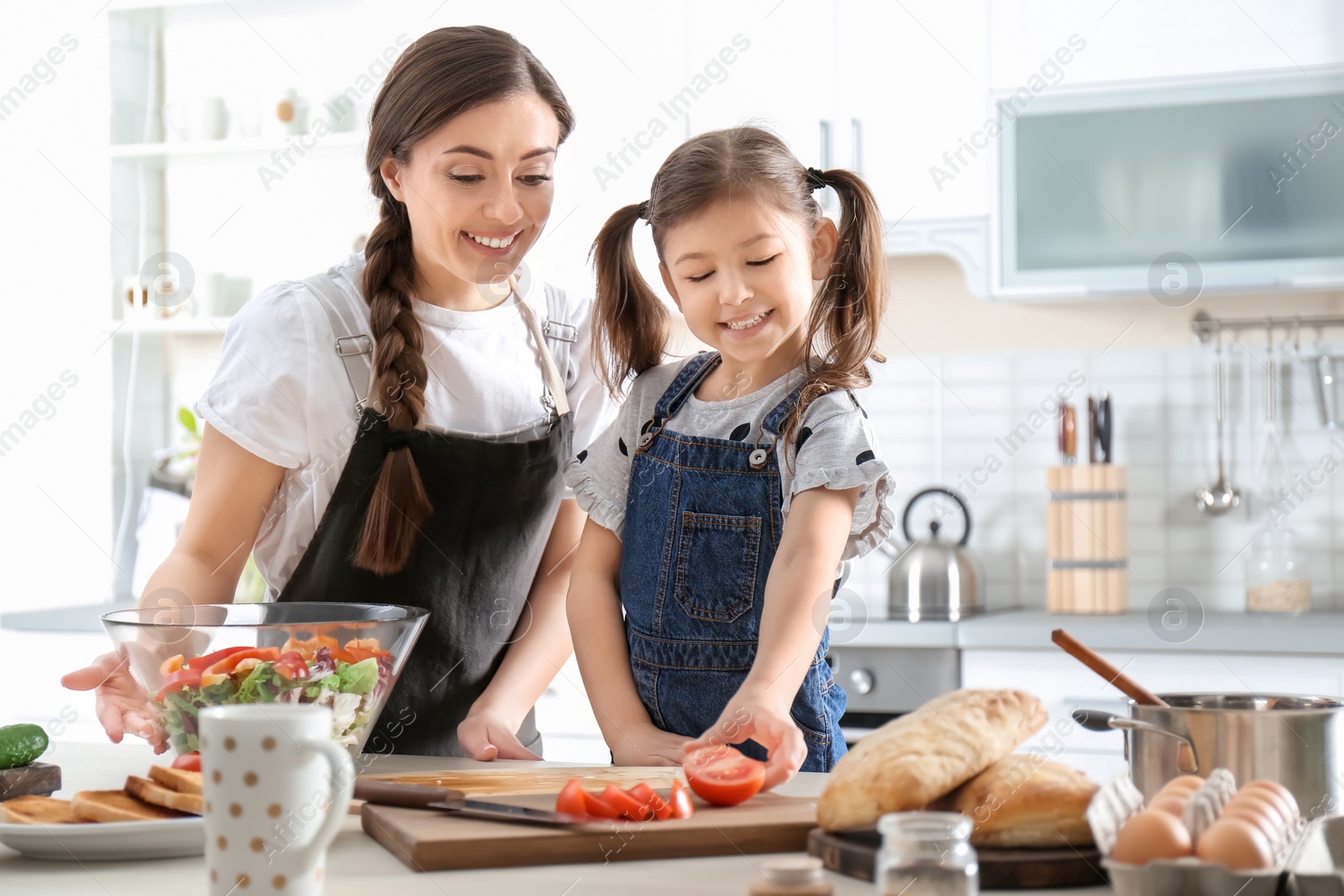 Photo of Young nanny with cute little girl cooking together in kitchen