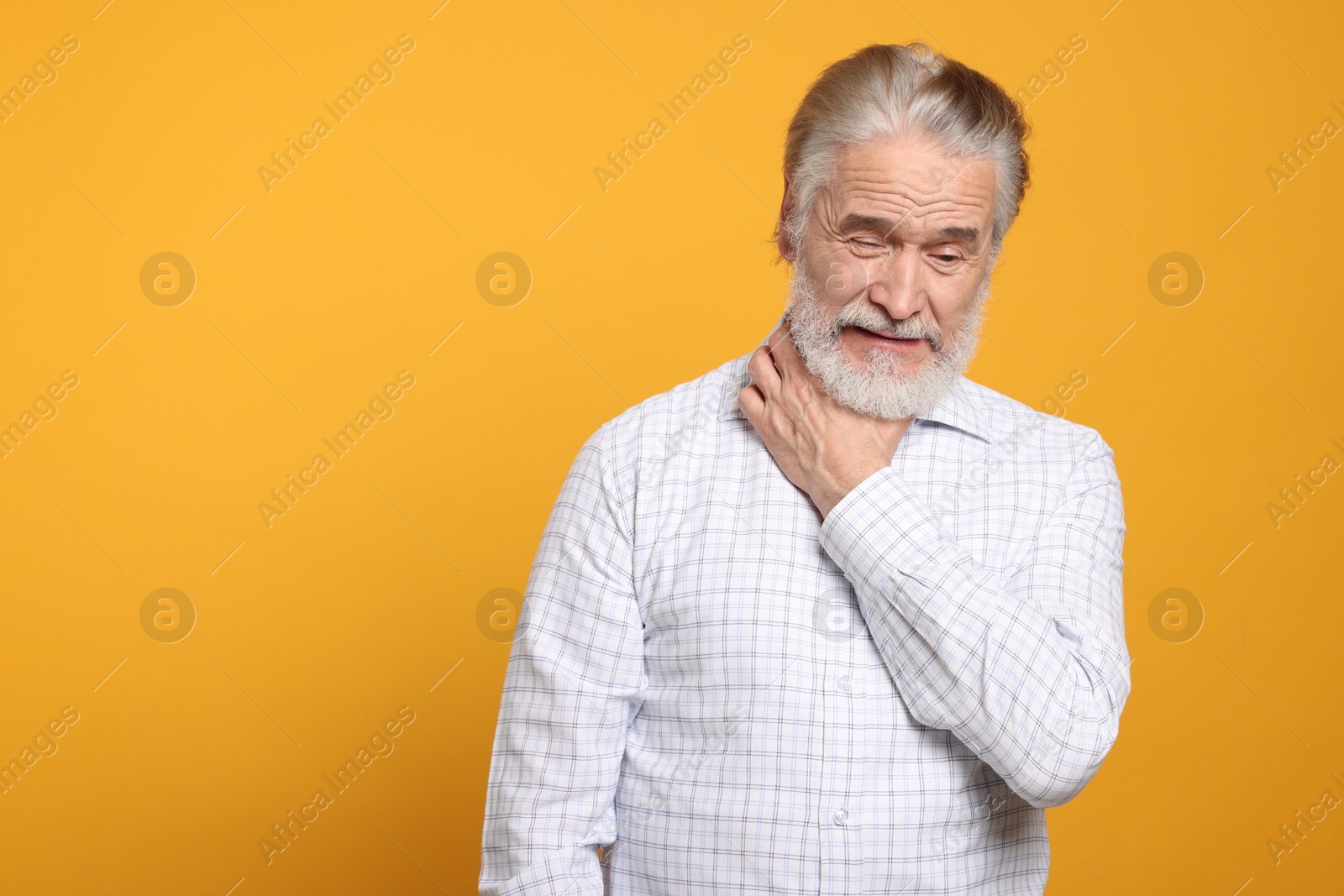 Photo of Senior man suffering from sore throat on yellow background, space for text. Cold symptoms
