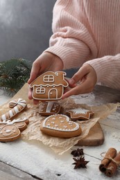 Woman holding delicious homemade Christmas cookie at wooden table, closeup