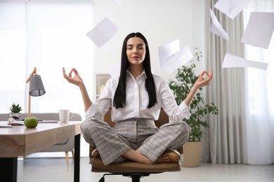 Photo of Young woman meditating at workplace. Stress relief exercise