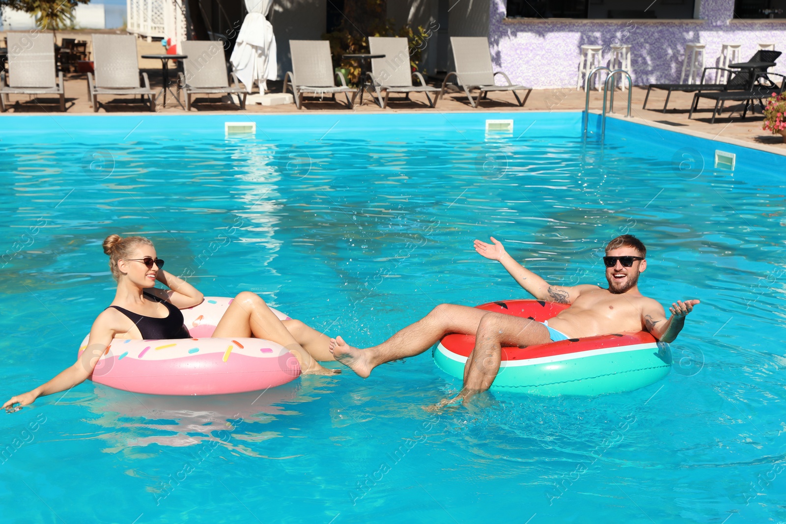 Photo of Happy young couple with inflatable rings in swimming pool