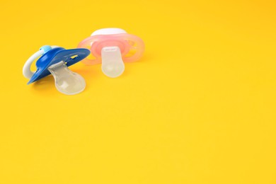 Photo of Colorful baby pacifiers on orange background. Space for text
