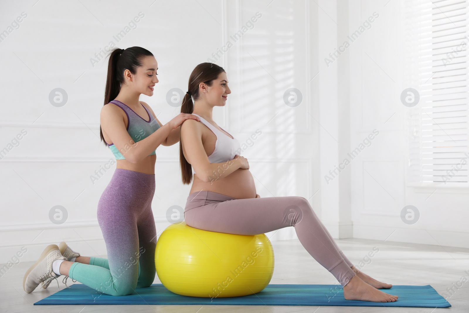 Photo of Trainer working with pregnant woman in gym. Preparation for child birth