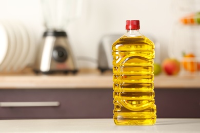 Photo of Bottle of oil on table against blurred background. Space for text