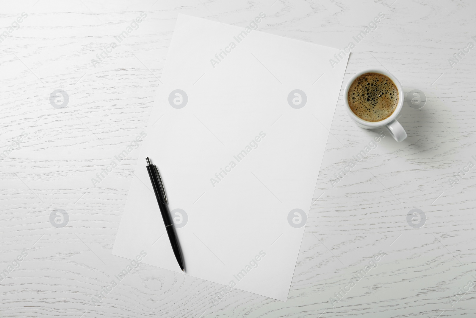 Photo of Blank paper sheet, pen and cup of coffee on white wooden table, flat lay. Space for text