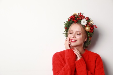 Photo of Beautiful young woman wearing Christmas wreath on white background. Space for text