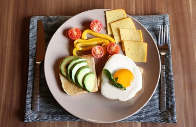 Photo of Tasty toasts with fried egg, avocado, cheese and vegetables served on wooden table, top view