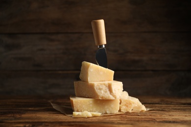 Photo of Delicious parmesan cheese and knife on wooden table
