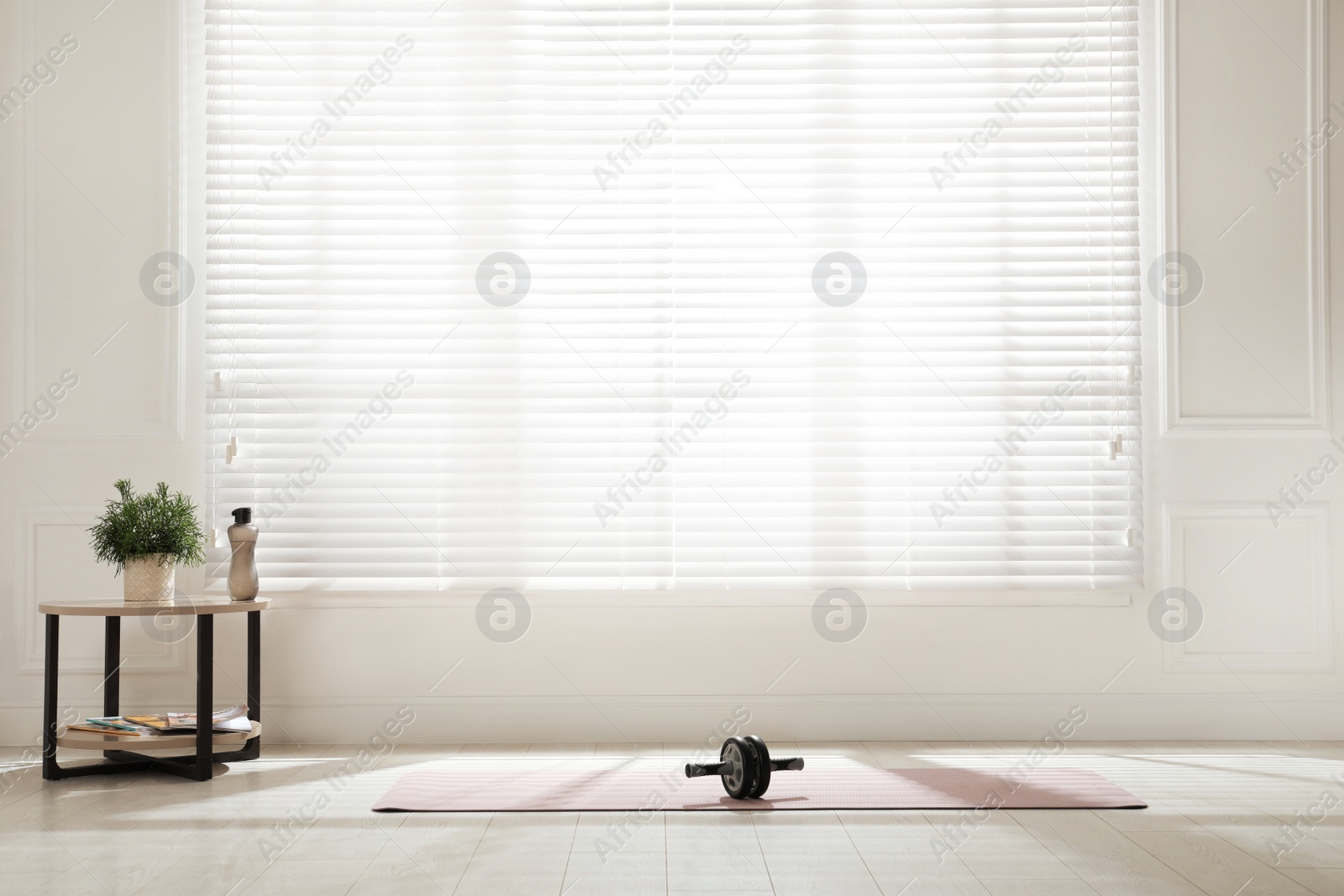 Photo of Exercise mat with ab roller near window in spacious room