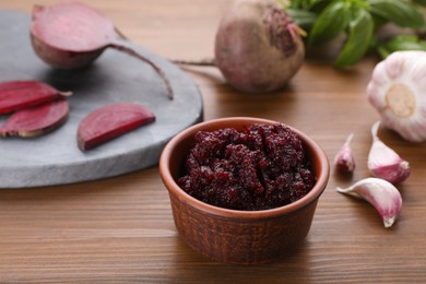 Bowl with tasty beet puree and ingredients on wooden table