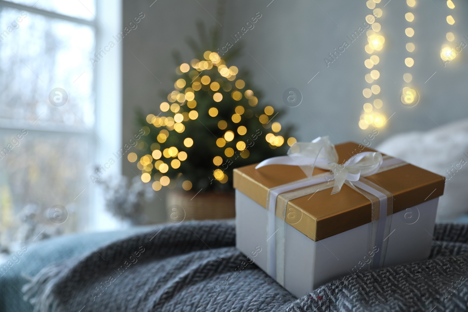 Photo of Christmas gift box on bed in festive interior