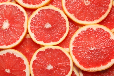 Photo of Juicy grapefruit slices as background, top view. Citrus fruit