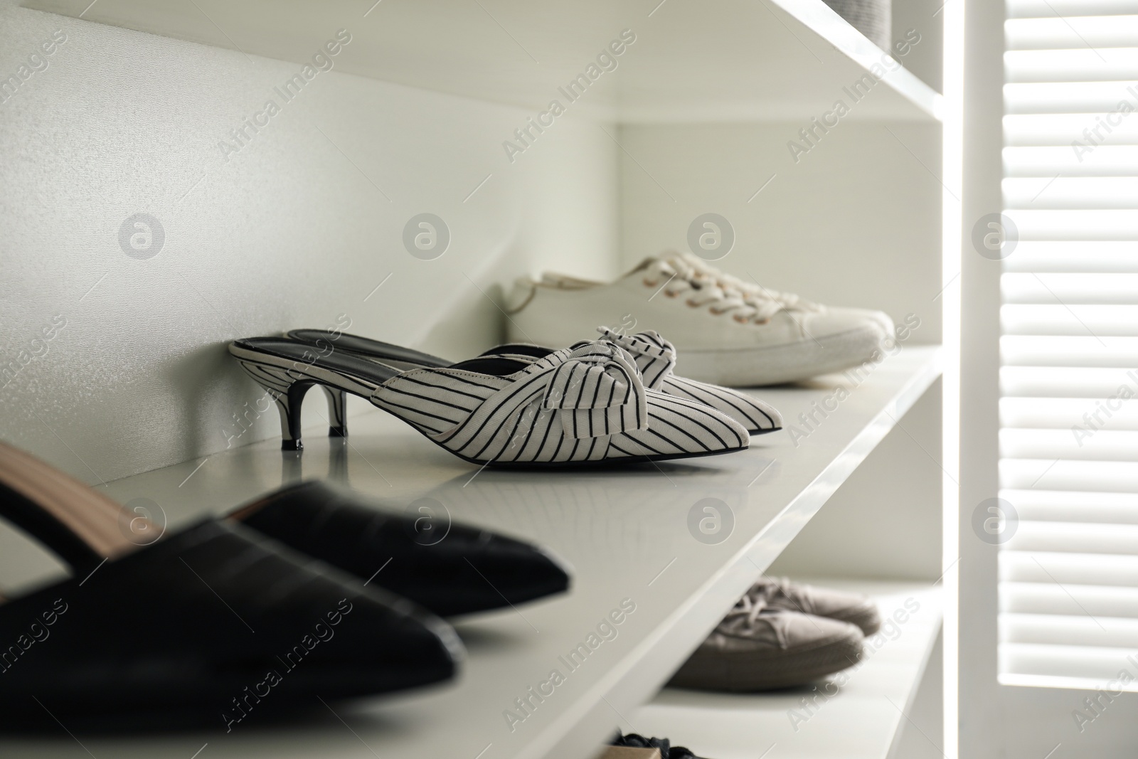 Photo of Storage rack with stylish women's shoes indoors, closeup