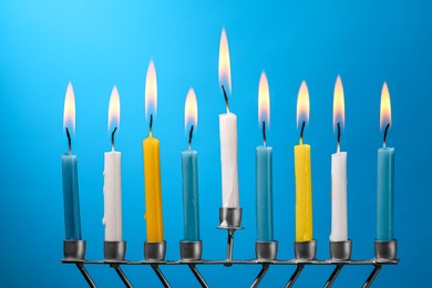 Hanukkah celebration. Menorah with burning candles on light blue background, closeup