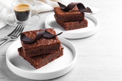 Photo of Delicious chocolate brownies served on white wooden table. Space for text