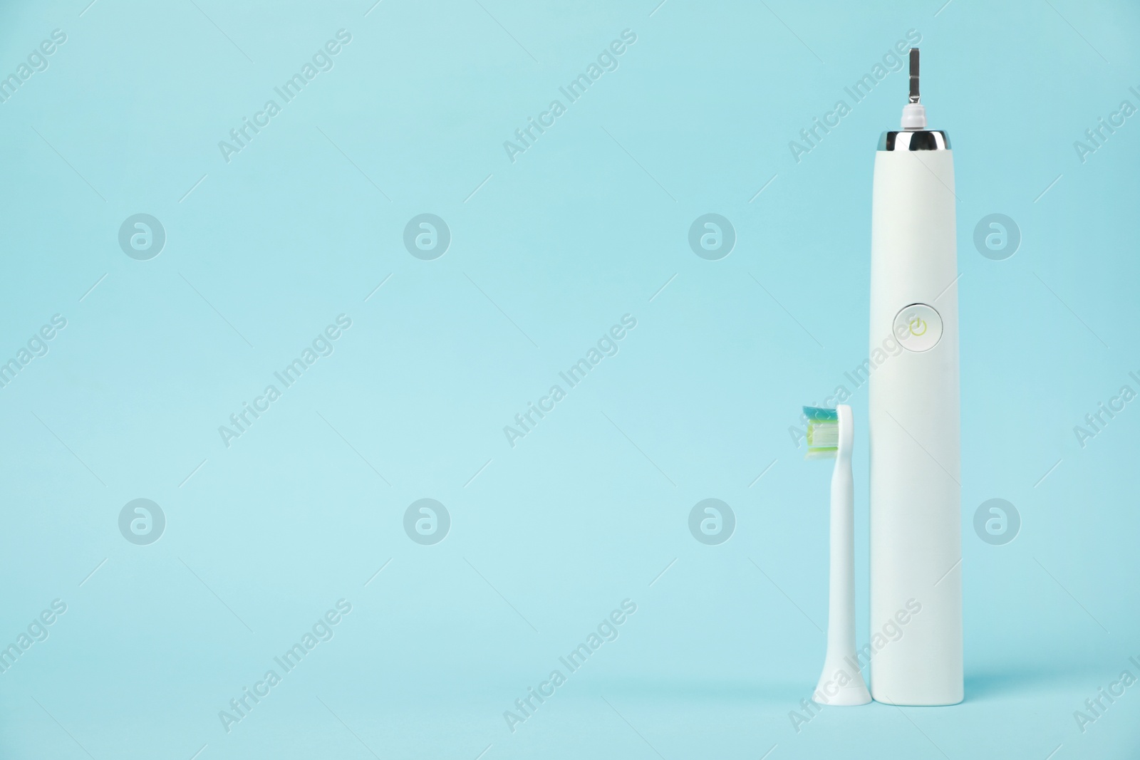 Photo of Electric toothbrush on light blue background, space for text