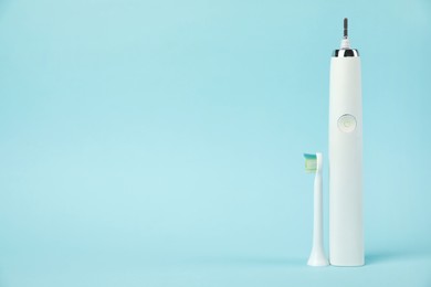 Electric toothbrush on light blue background, space for text