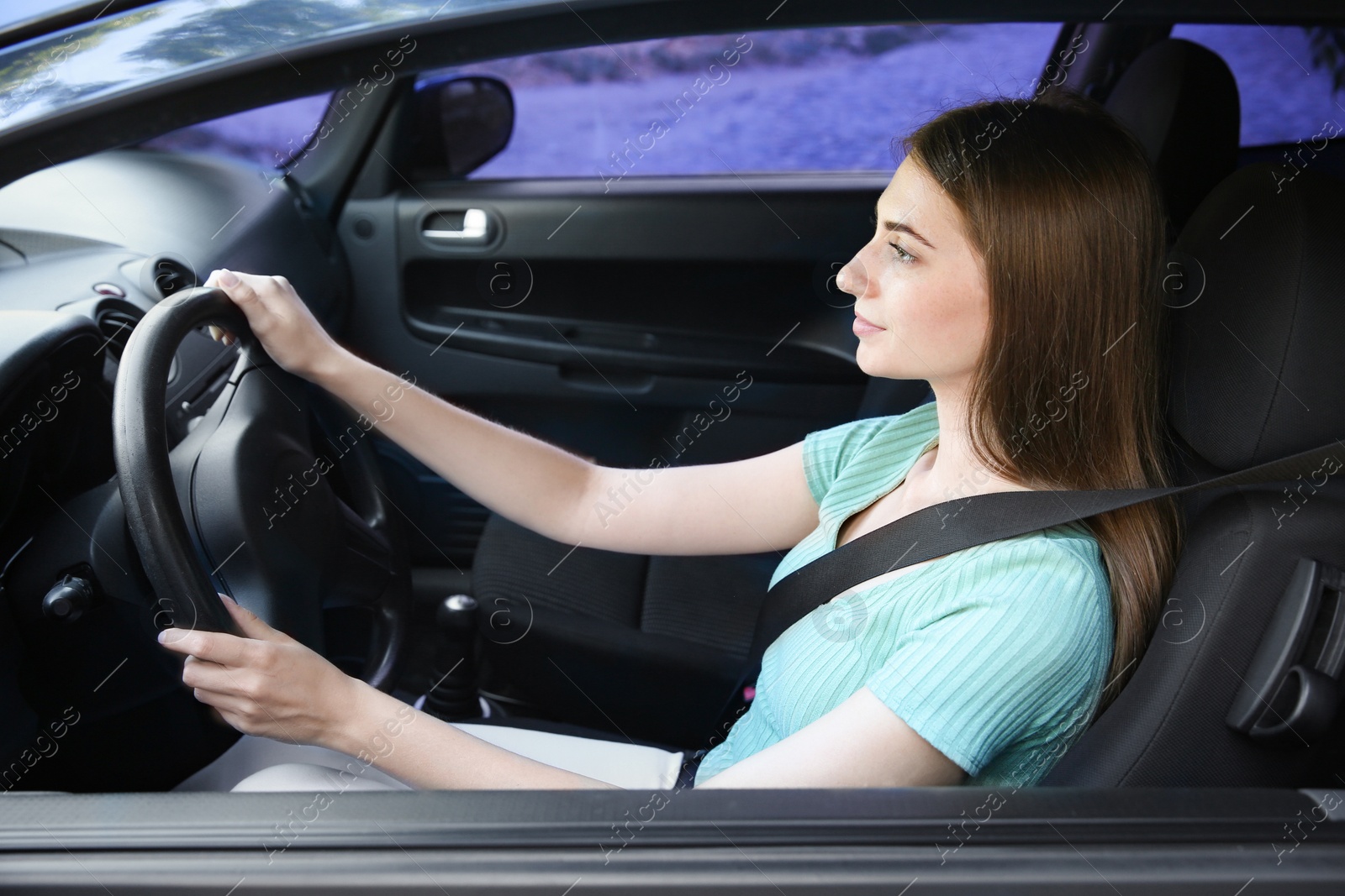 Photo of Young woman with fastened safety belt on driver's seat in car