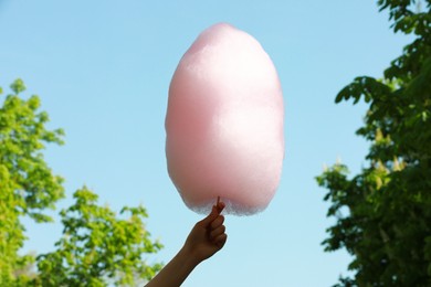 Photo of Woman holding sweet cotton candy against blue sky, closeup