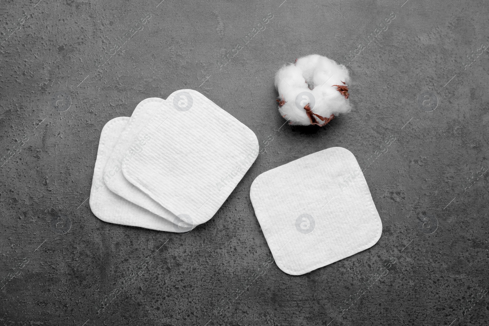 Photo of Many clean cotton pads and flower on grey background, flat lay