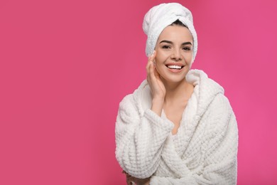 Photo of Happy young woman in bathrobe with towel on head against pink background, space for text. Washing hair