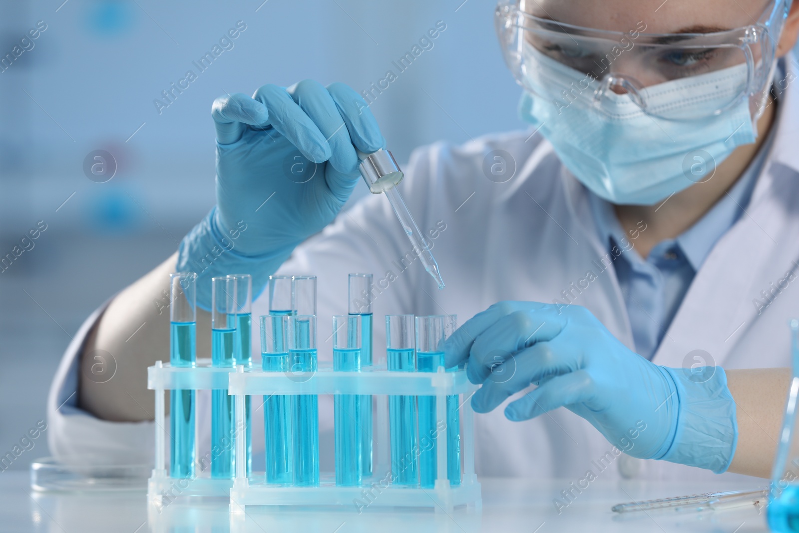 Photo of Scientist dripping liquid from pipette into test tube in laboratory