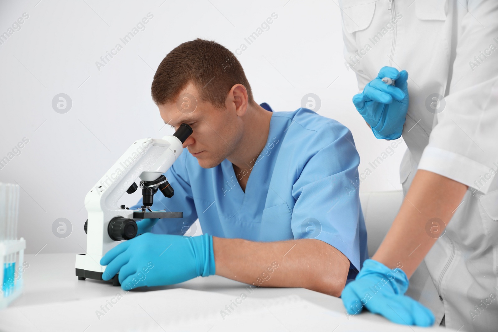 Photo of Scientist using microscope at table and colleague in laboratory. Medical research