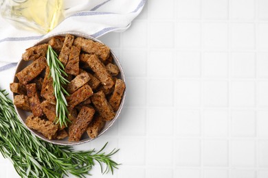 Photo of Crispy rusks with rosemary on white tiled table, flat lay. Space for text