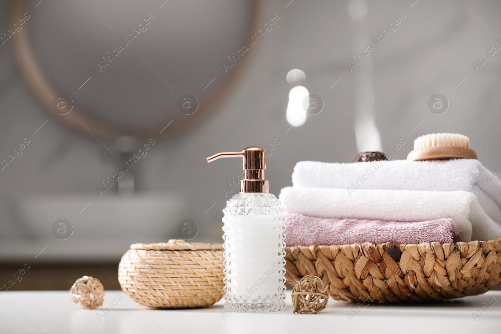 Photo of Soap dispenser, towels and brush on white table indoors