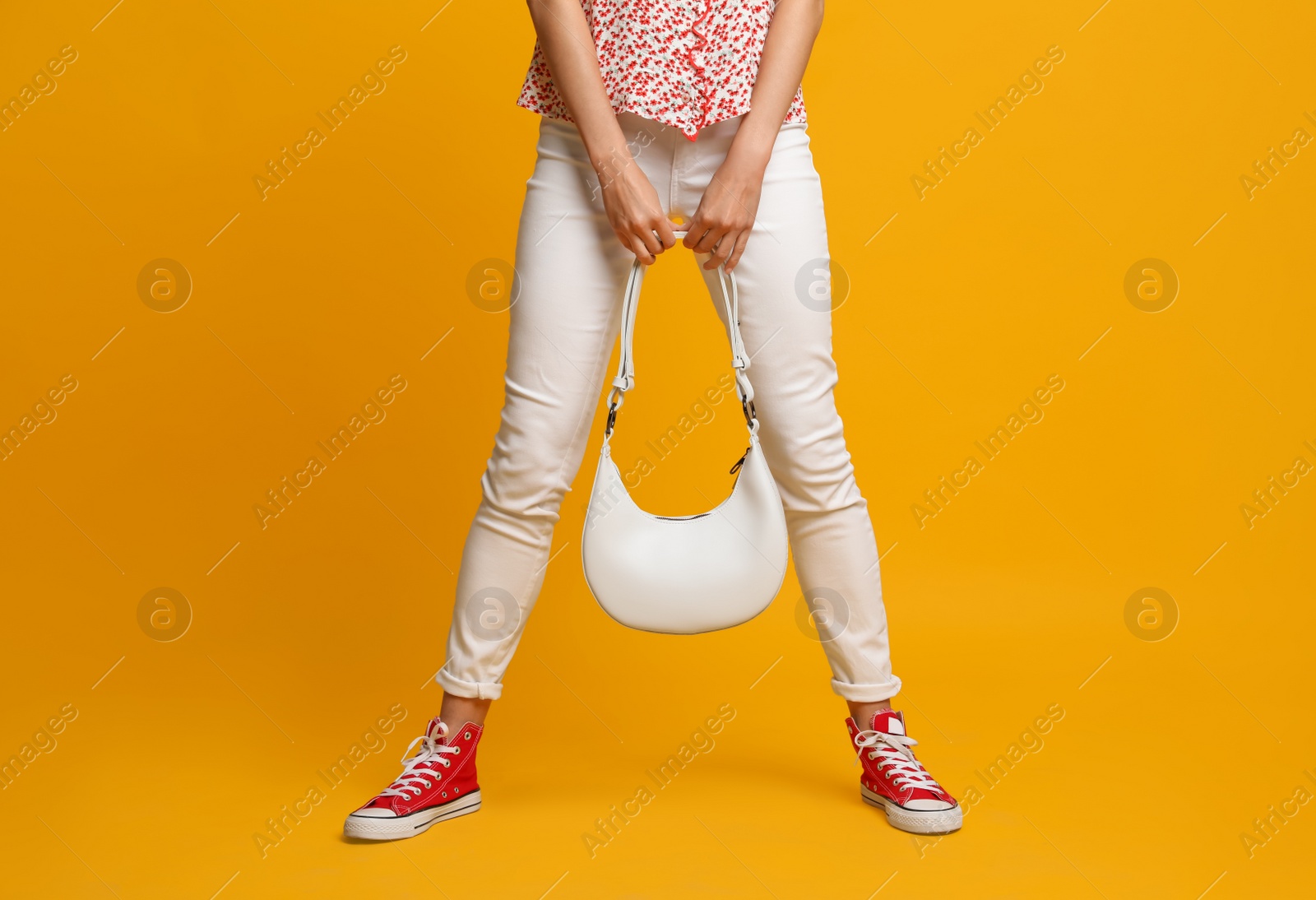 Photo of Stylish woman with trendy baguette bag on yellow background, closeup