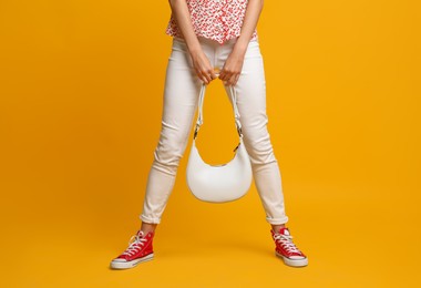 Stylish woman with trendy baguette bag on yellow background, closeup