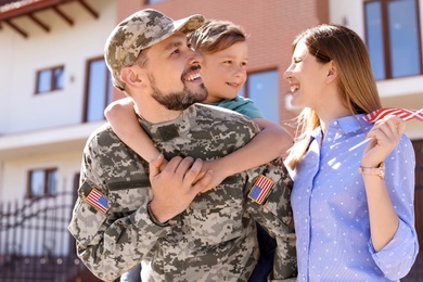 Photo of Male soldier reunited with his family outdoors. Military service