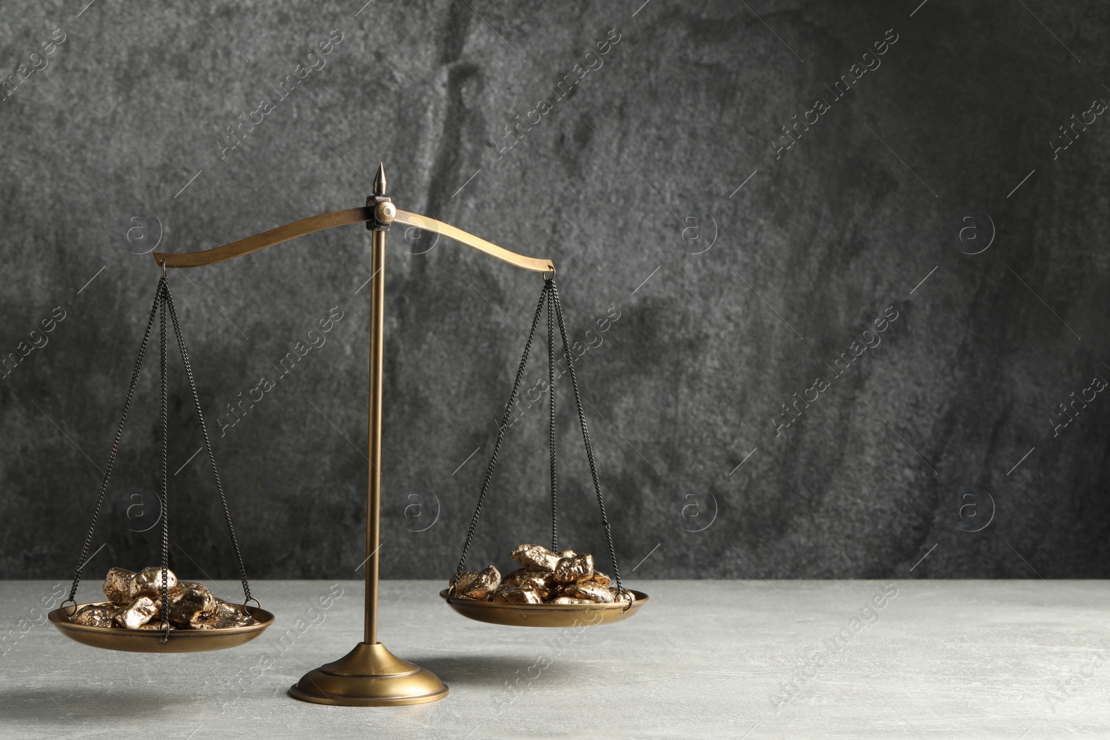 Photo of Vintage scales with gold nuggets on light table against grey background, space for text