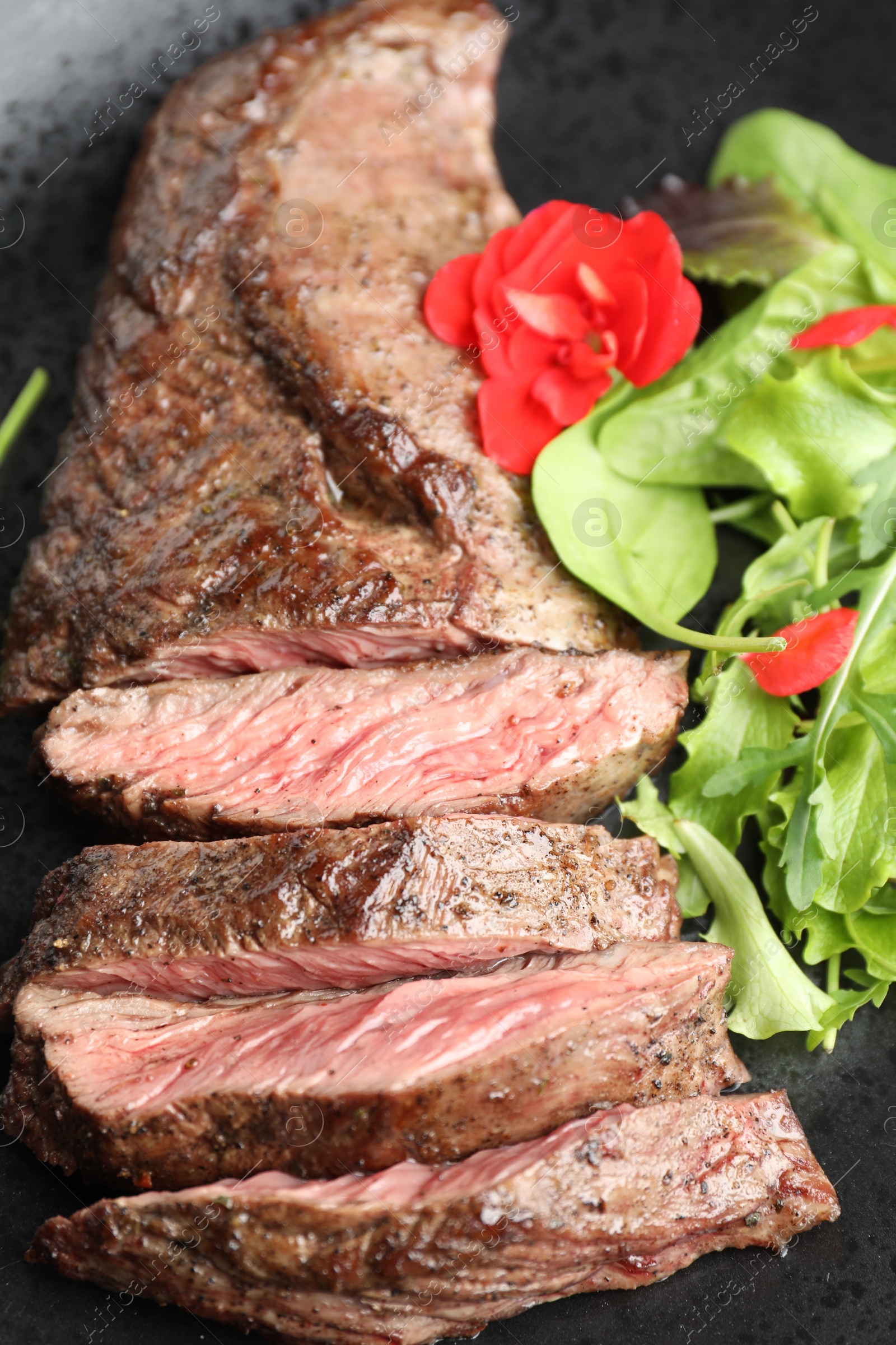 Photo of Pieces of delicious grilled beef meat and greens on plate, closeup