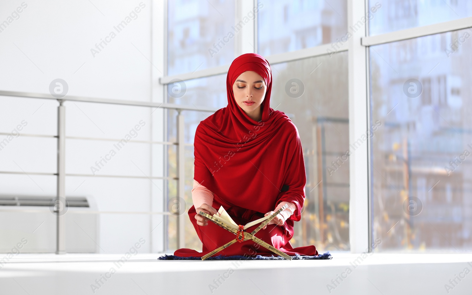 Photo of Muslim woman in hijab reading Koran indoors