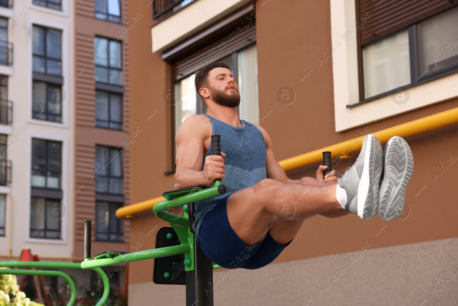 Photo of Man doing leg rise exercise at outdoor gym