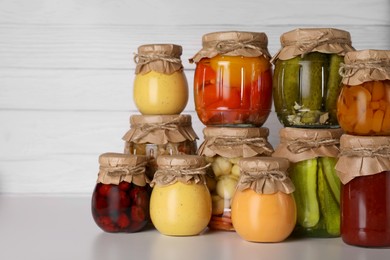 Many jars with different preserved products on light grey table. Space for text