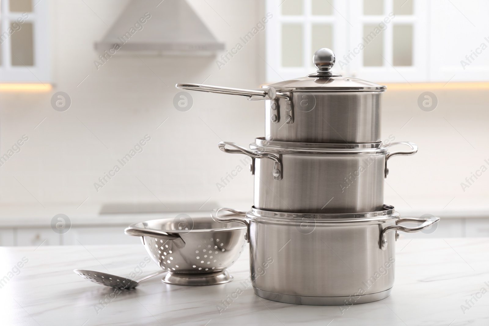 Photo of Set of stainless steel cookware and kitchen utensils on white table indoors