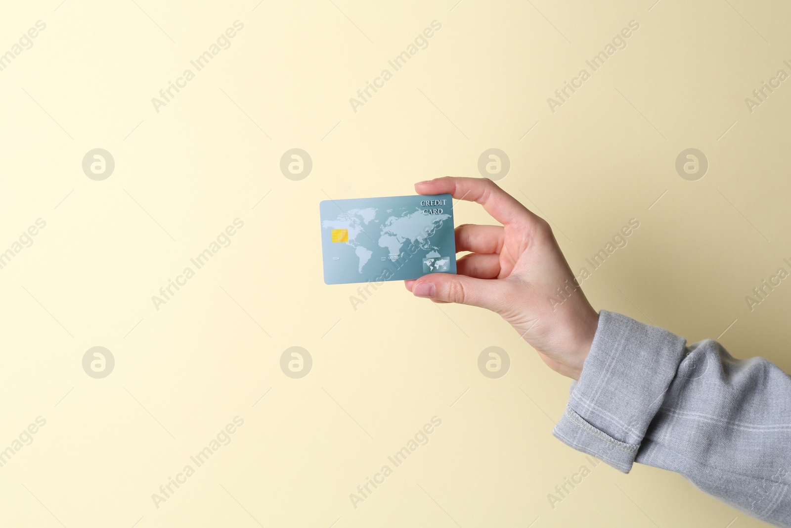 Photo of Woman holding credit card on beige background, closeup