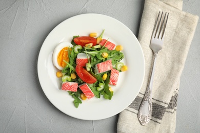 Photo of Delicious crab stick salad served on grey table, flat lay