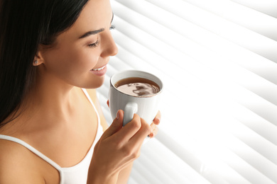 Young woman with cup of tea near window. Lazy morning