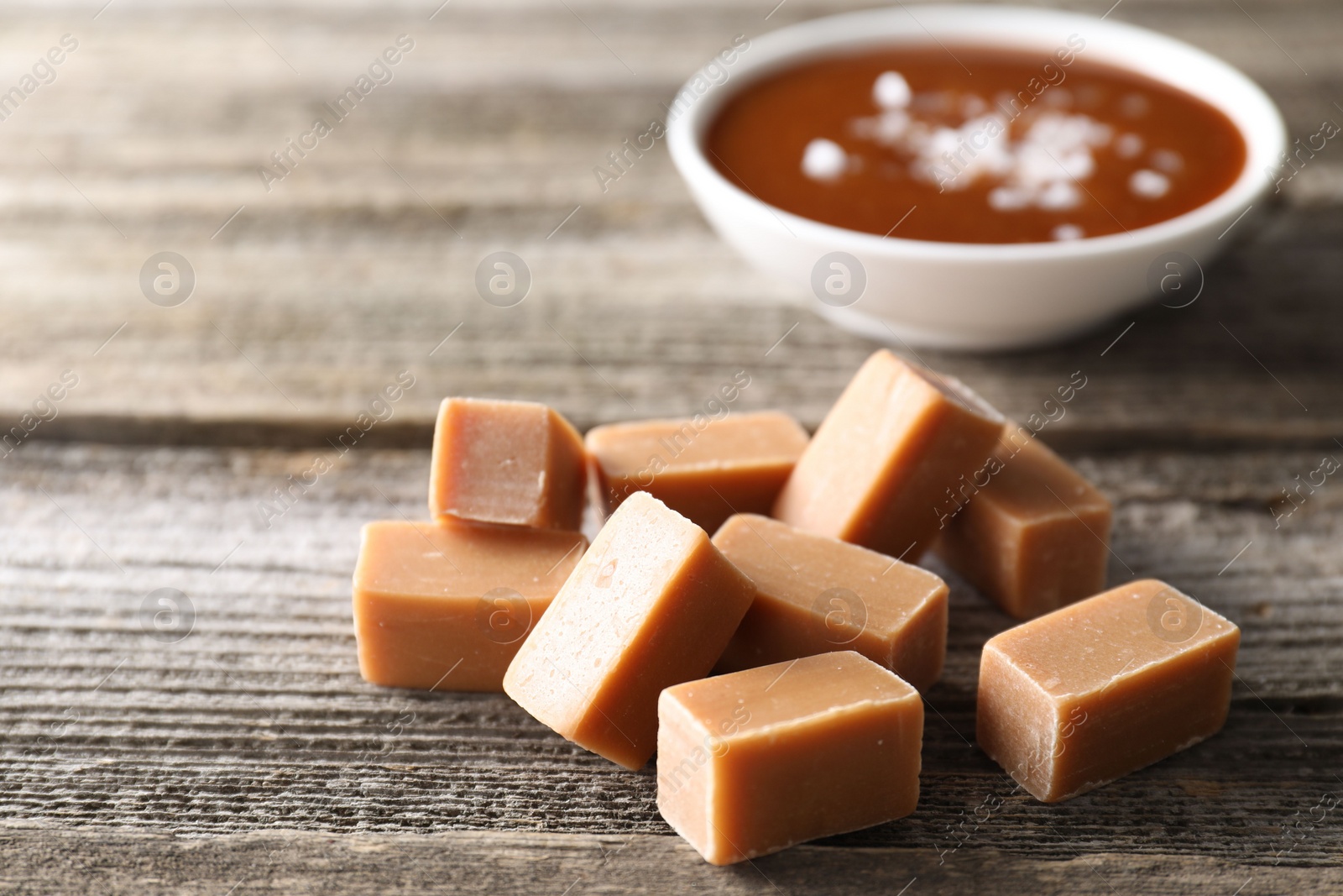 Photo of Yummy caramel candies on wooden table, closeup