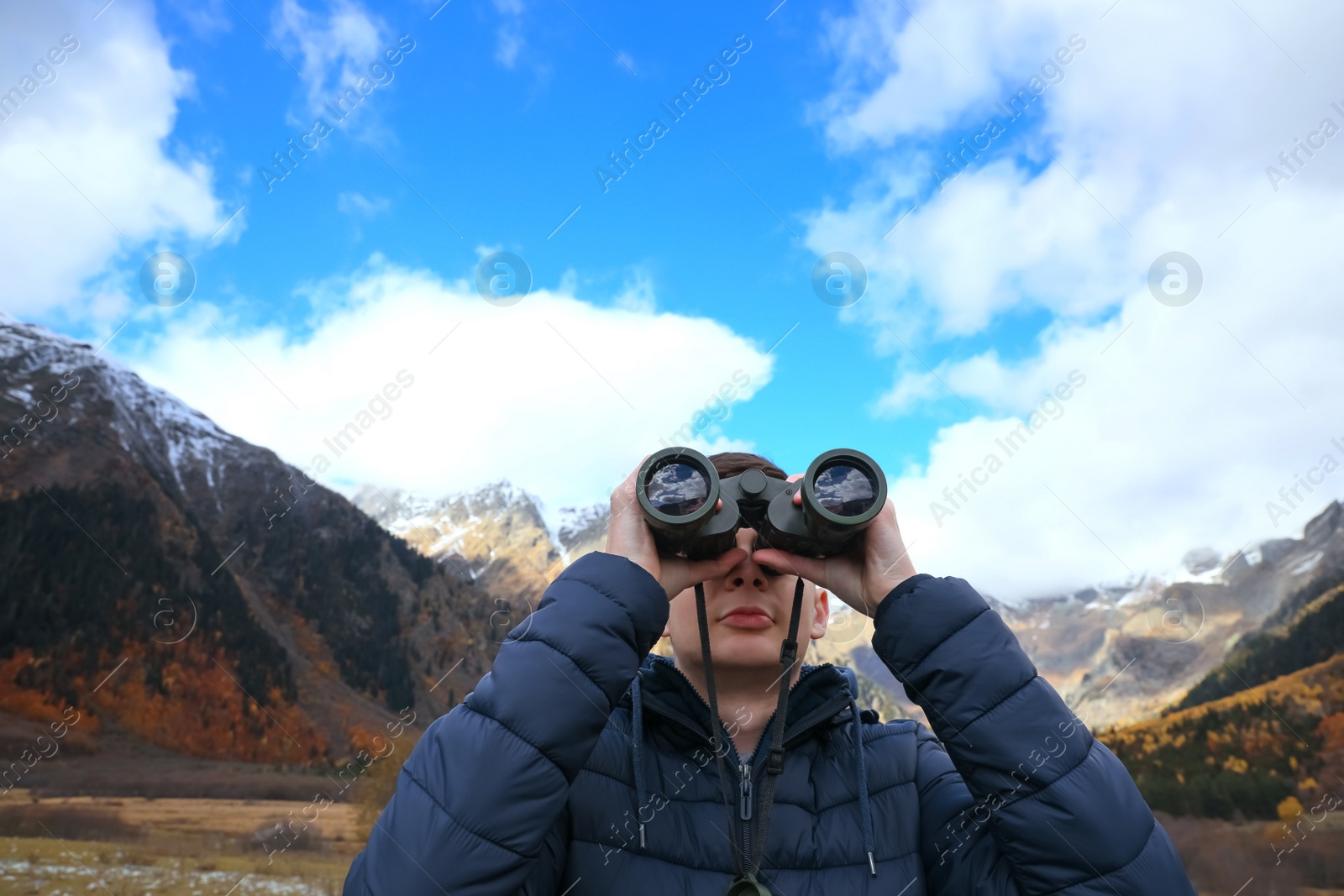 Photo of Boy looking through binoculars in beautiful mountains