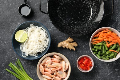 Flat lay composition with black wok and products on dark textured table