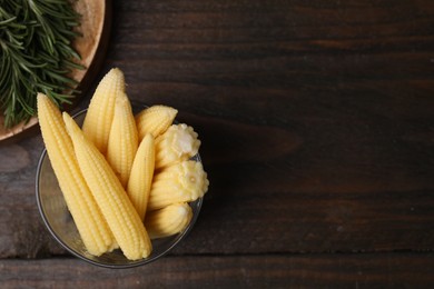 Photo of Tasty fresh yellow baby corns in glass on wooden table, top view. Space for text