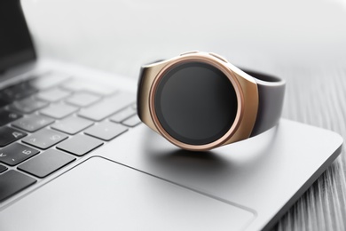 Photo of Stylish smart watch on laptop, closeup view