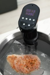 Photo of Sous vide cooker and vacuum packed meat in pot on table, closeup. Thermal immersion circulator